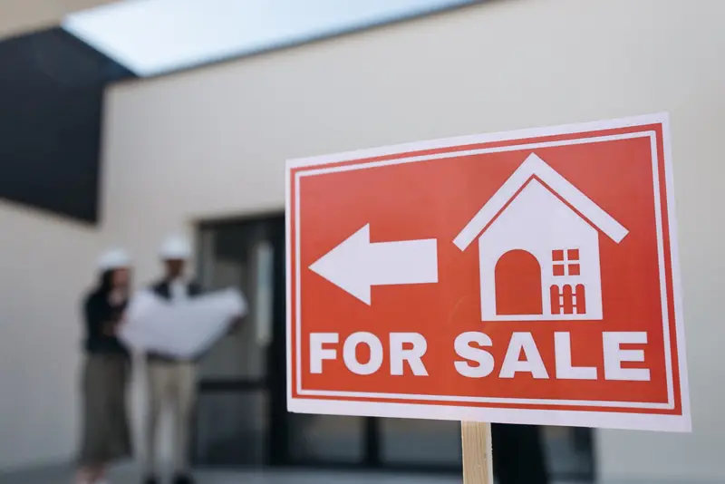 A residential house listed for sale with a for sale sign on the lawn