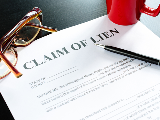 Claim of lien being filed by a property owner over work on a construction project with a binding contract with a pair of glasses a pen and a red coffee mug on top of the claim form