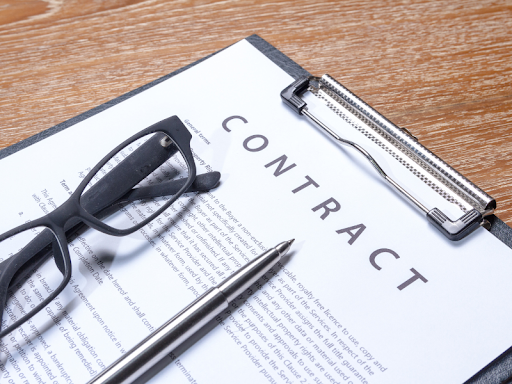 A construction contract between a contractor and a client about the construction project they will be working on with a pair of glasses and a pen lying on top of the contract