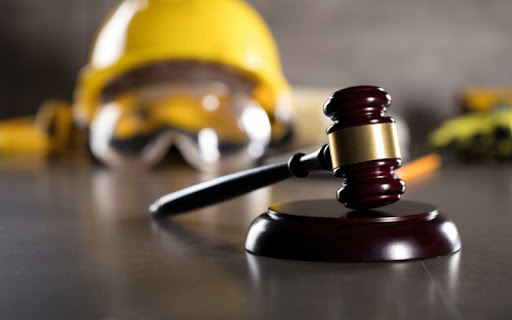 A gavel with a construction hard had and safety goggles in the background symbolizing that lawyers from ATAC Law are experts in construction.