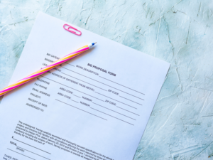 A bid proposal form for a construction project with a pink pencil and paperclip on top of the form