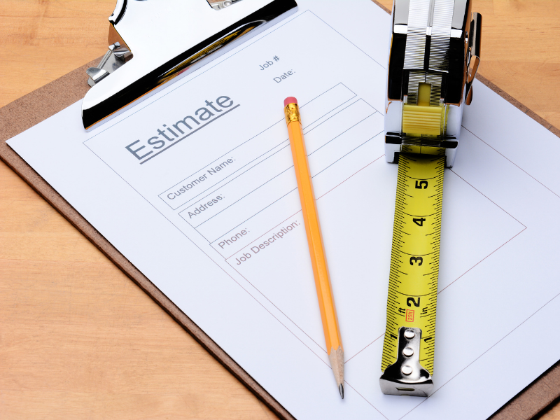 an estimate for the cost of a construction job with a pencil and tape measure lying on top