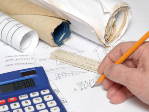 Construction contractor using a pencil and calculator to add up total cost estimation for a project as a formal quote