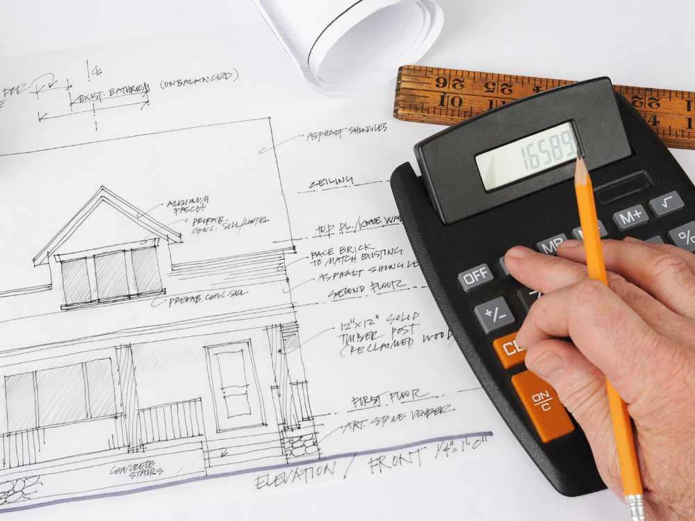 contractor using a calculator and plans to calculate a cost estimate for a client